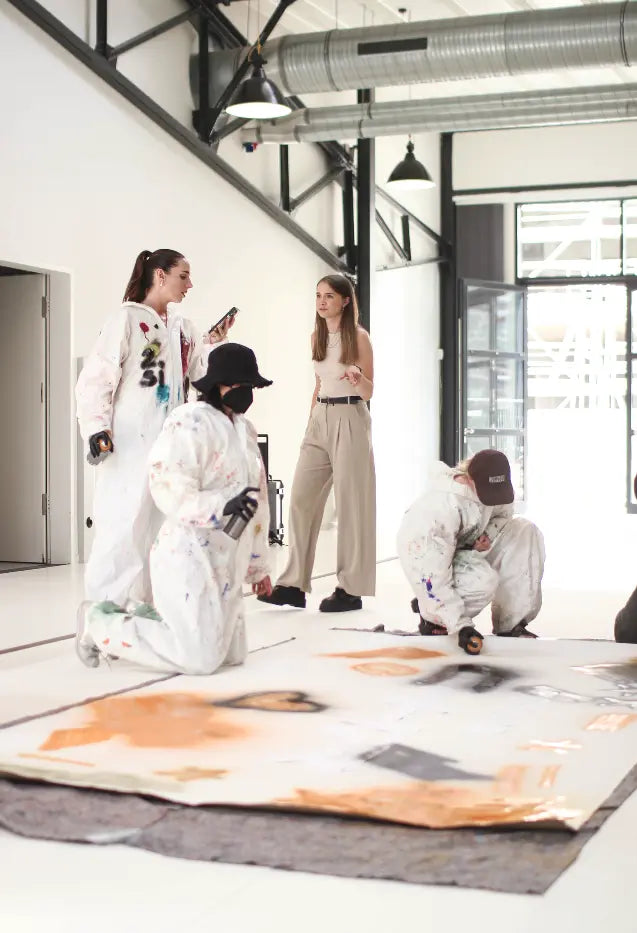Graffiti-Workshop: Team steht vor einer großen Wand und stimmt das gemeinsame Motiv ab