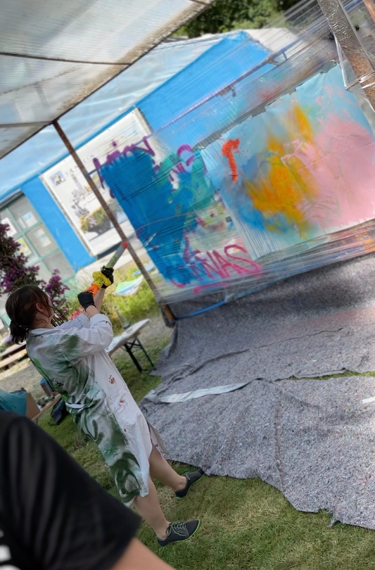 Teilnehmerin wirft Farbe auf eine Leinwand beim Action Painting Team Event im Freien