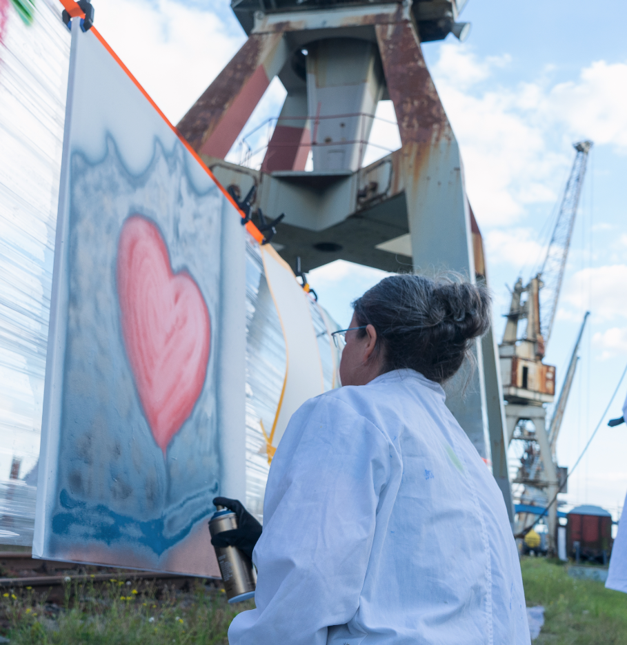 Spraydosen und Acrylfarben auf dem Pier vor der MS Bleichen, im Hintergrund ein Frachtschiff im Hamburger Hafen