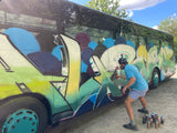 Person mit Atemschutz spruehte ein grosses Graffiti-Piece auf die Seite eines Reisebusses