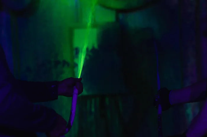 Grüner Farbstrahl aus einem Schlauch unter Schwarzlicht bei einem Action-Painting-Termin