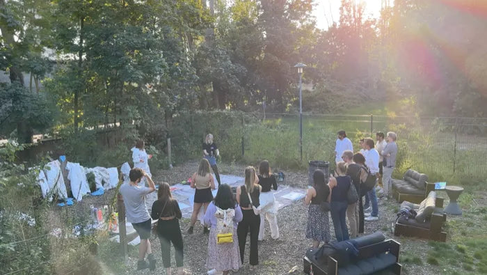 Gruppe von Teilnehmenden steht abends bei tiefstehender Sonne auf einer Kiesfläche im Freien