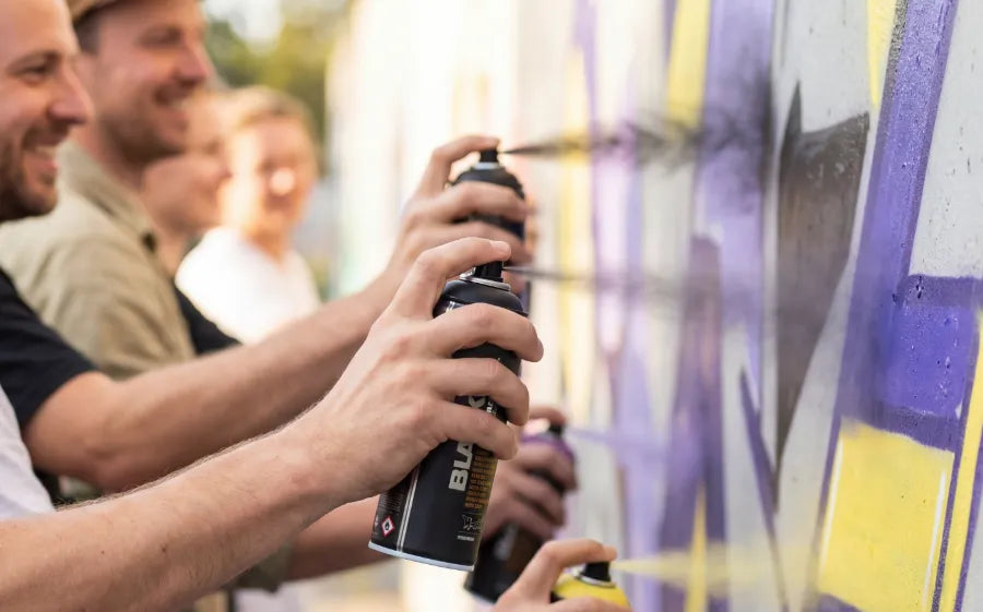 Hände mit Sprühdosen bei der Arbeit an einem Graffiti-Piece
