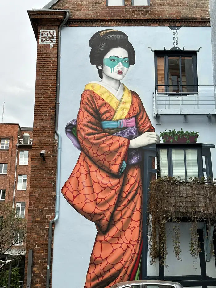 Eine Geisha im orangen Kimono auf einer Hauswand
