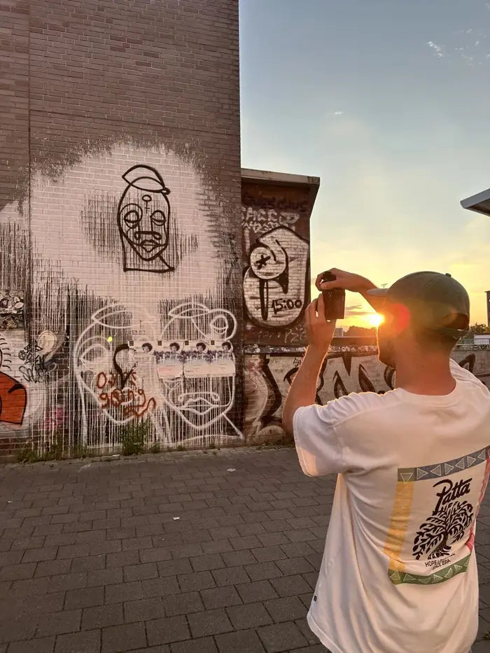 Eine Person fotografiert im Abendlicht Strichzeichnungen auf einer Backsteinwand
